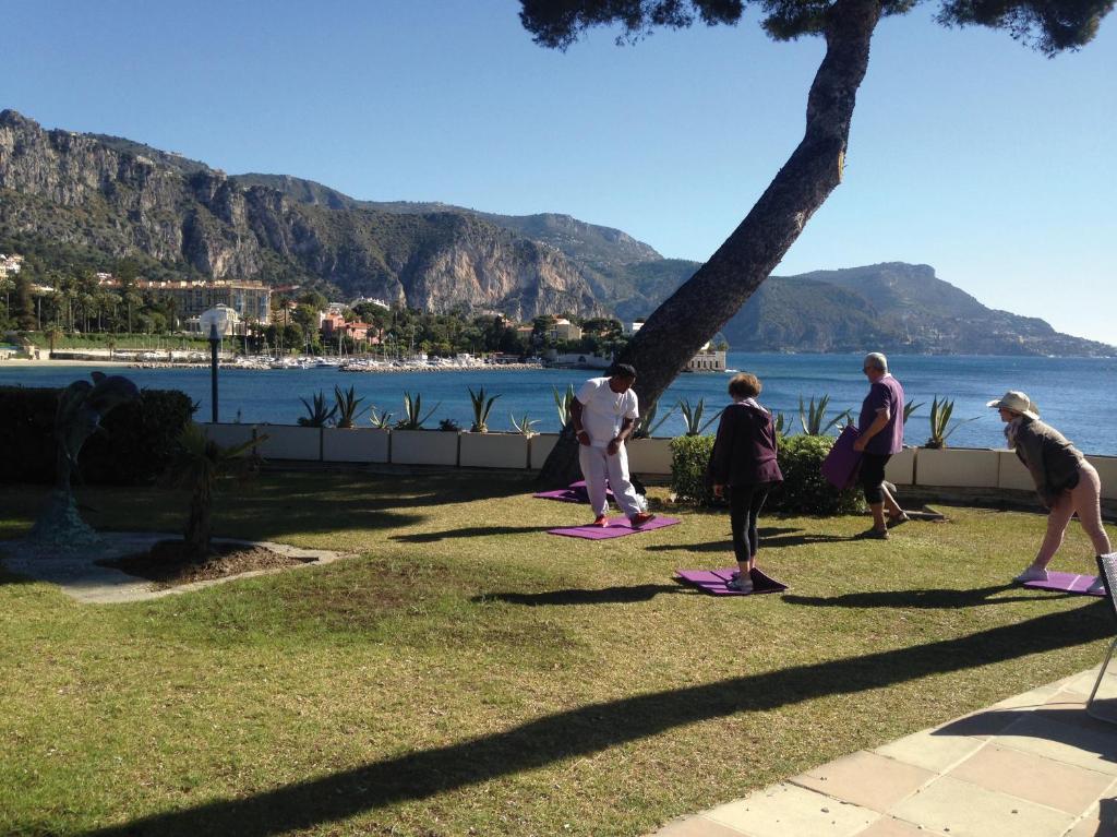 a group of people doing yoga by the water at Hôtel Vacances Bleues Delcloy in Saint-Jean-Cap-Ferrat
