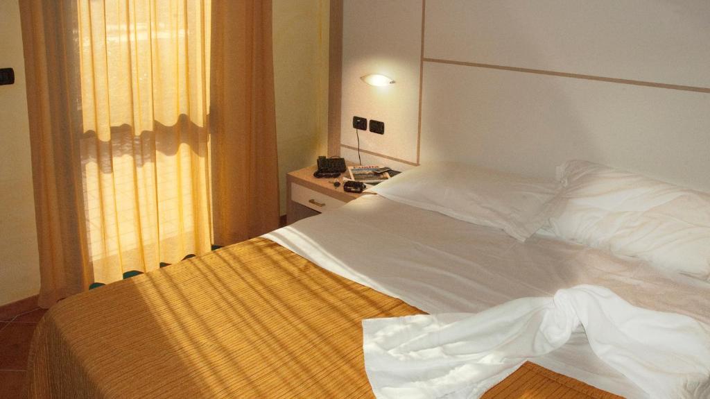 Cama blanca en habitación con ventana en Baiamalva Resort Spa, en Porto Cesareo