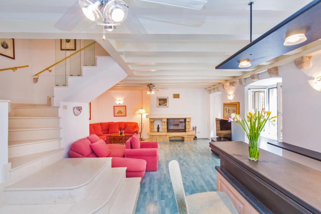 una sala de estar con muebles de color rojo y una escalera en Villa Leora Dubrovnik en Dubrovnik