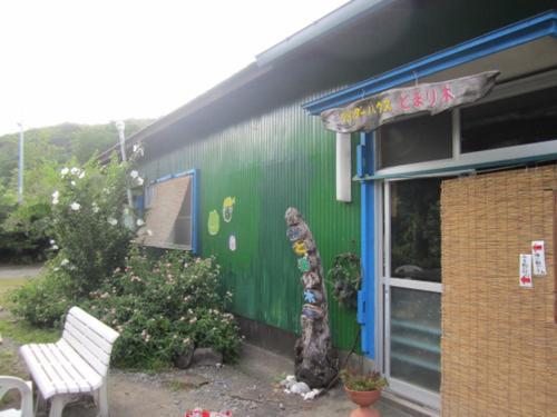 un bâtiment vert avec une statue à côté d'un banc dans l'établissement Tomarigi, à Yakushima