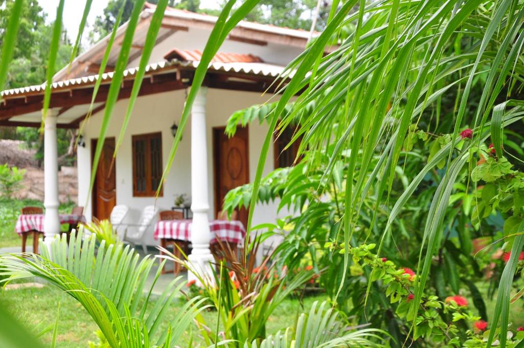 a small white house with a lot of green plants at Sigiriya Amenity Home Stay in Sigiriya