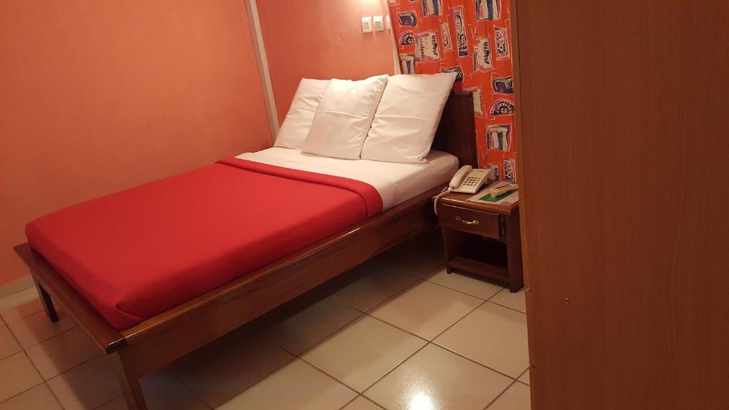 Cama pequeña en habitación pequeña con teléfono en Résidence Saint-Jacques Brazzaville, en Brazzaville