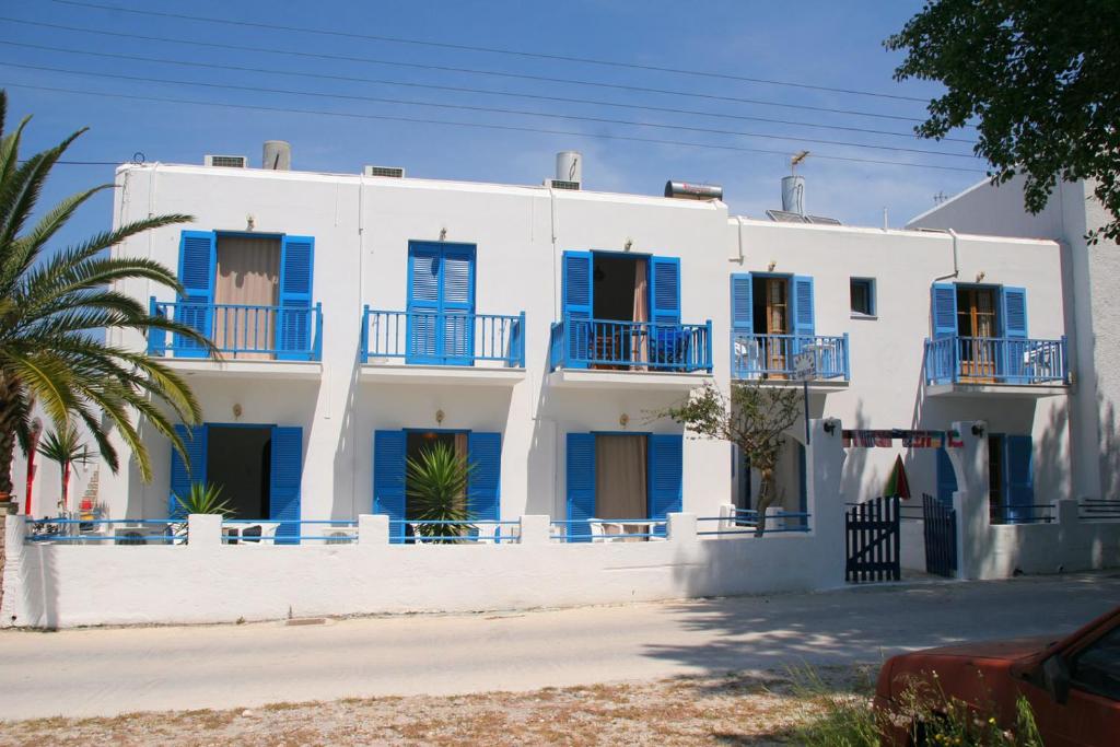 a white house with blue shutters and a palm tree at Pension Piertzovani in Parikia