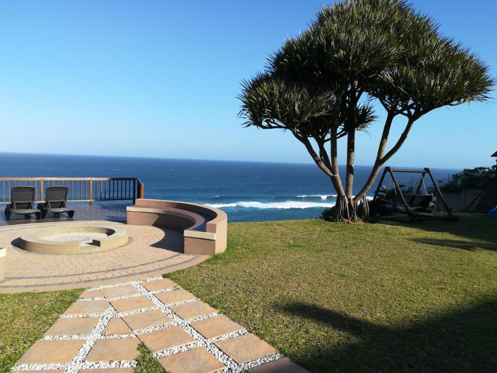 a patio with a tree and the ocean in the background at Beach Retreat Guesthouse in Amanzimtoti