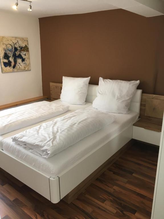 uma cama grande com lençóis brancos e almofadas em Ferienwohnung "Zur Ottoburg" in Schlitz em Schlitz