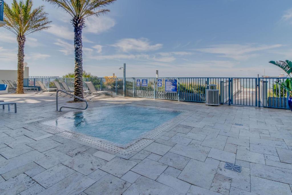 a swimming pool with palm trees and a fence at Sterling Breeze 2 in Panama City Beach