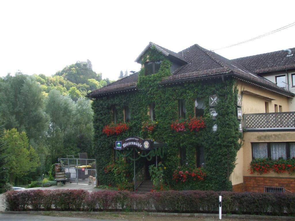 un edificio cubierto de hiedra con flores. en Landgasthof Wiesenmühle, en Burg Hohenstein