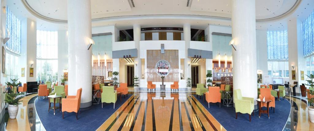 a lobby with tables and chairs in a building at Concorde Hotel Fujairah in Fujairah