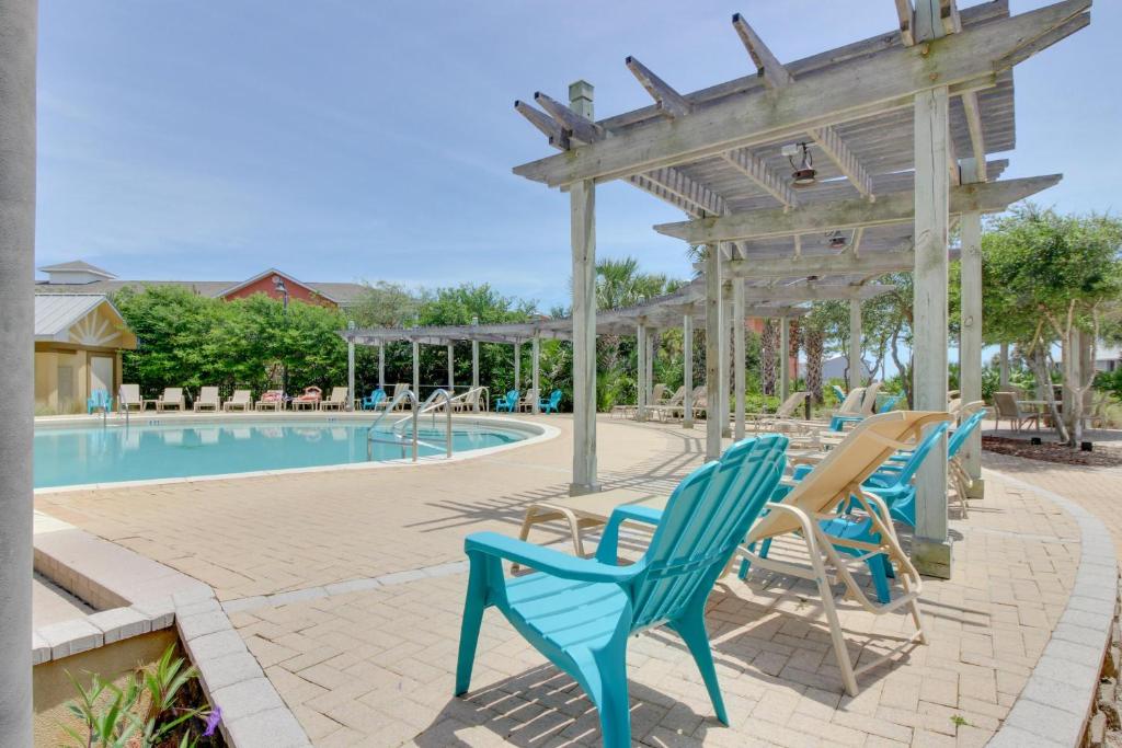 uma piscina com cadeiras azuis e uma pérgola de madeira em The Beach Resort em Destin