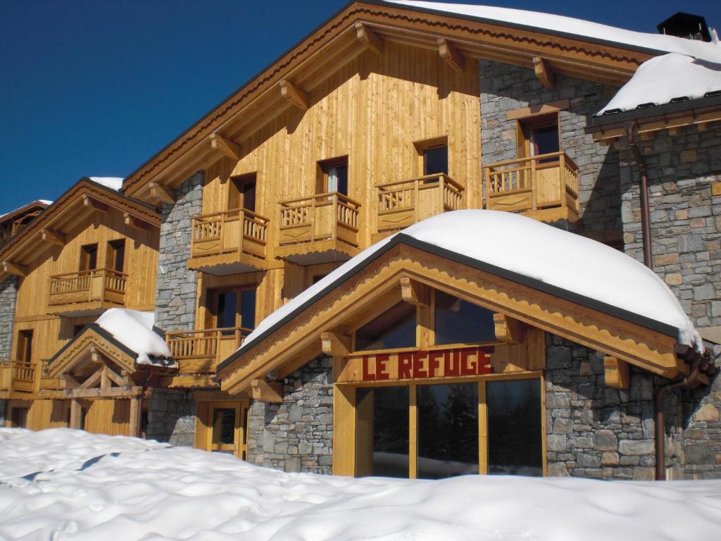 un lodge dans la neige avec un panneau indiquant le refuge dans l'établissement Le Refuge, à La Rosière