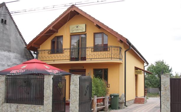 een geel huis met een rode paraplu ervoor bij Vila Korona in Satu Mare