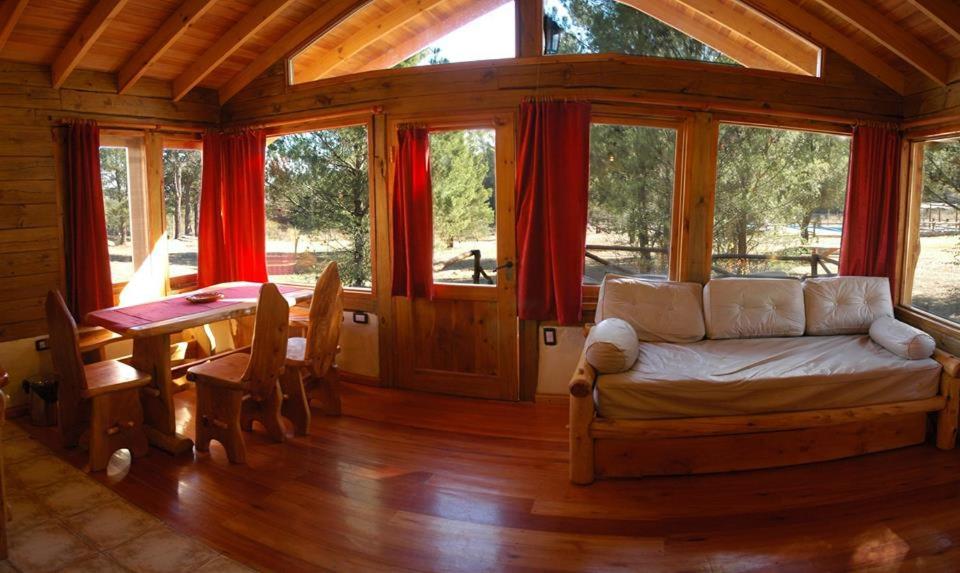 Habitación con cama, mesa y ventanas. en Cabañas Bosques del Sol en Villa Giardino