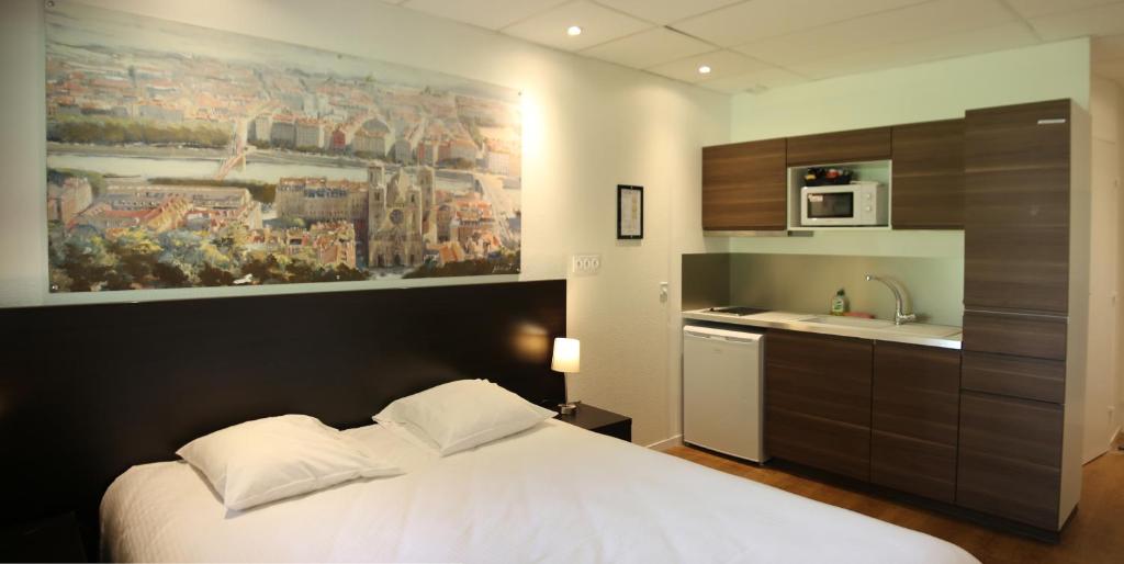 a bedroom with a white bed and a kitchen at Quadraverde in Lyon