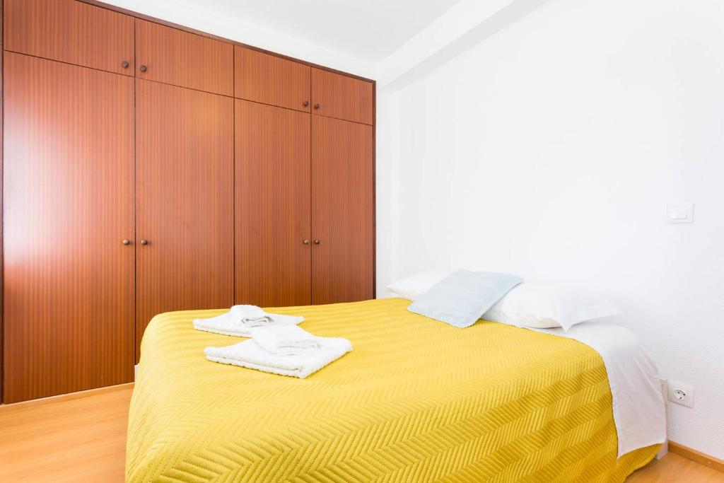 1 dormitorio con 1 cama amarilla y armarios de madera en Cegonha do mar, en Aljezur