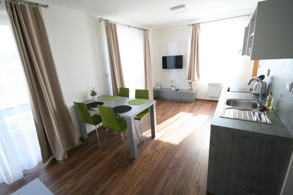 a kitchen with a table and green chairs in a room at Apartmány Apollon Resort Lednice in Lednice