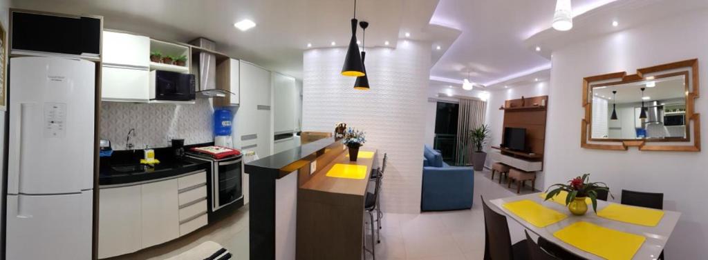 a kitchen with white cabinets and yellow accents at Praia do Forte Flat in Cabo Frio