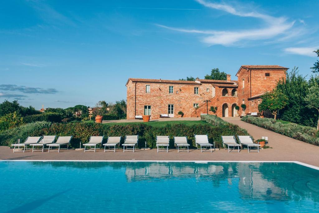 a group of chairs and a pool in front of a building at Casale Cardini in Foiano della Chiana