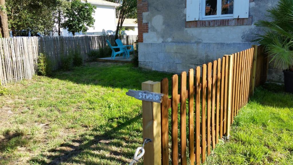 une clôture en bois dans une cour à côté d'une maison dans l'établissement STUDIO 300m DE LA PLAGE, à Soulac-sur-Mer