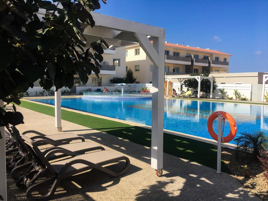 a swimming pool with lounge chairs next to a building at Mythical Sands Resort - Good Vibes Apartment in Paralimni