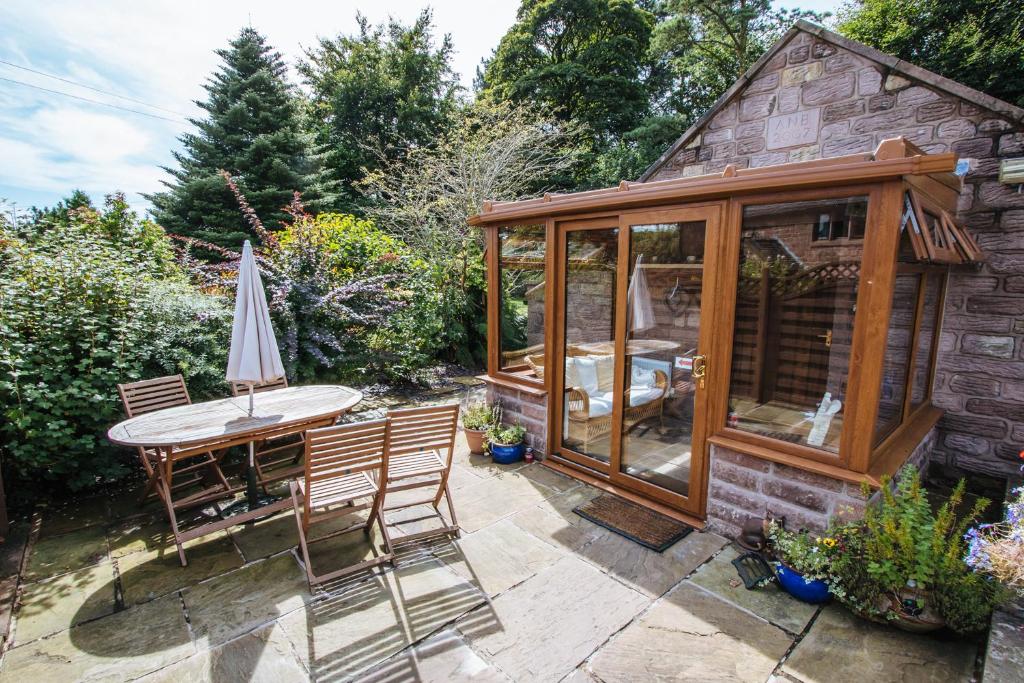 a conservatory with a table and chairs in a garden at Willow cottage with private hot tub in Upper Hulme