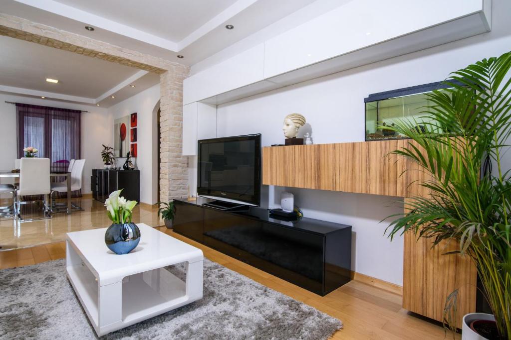 sala de estar con TV y mesa blanca en Apartments Gea en Trogir