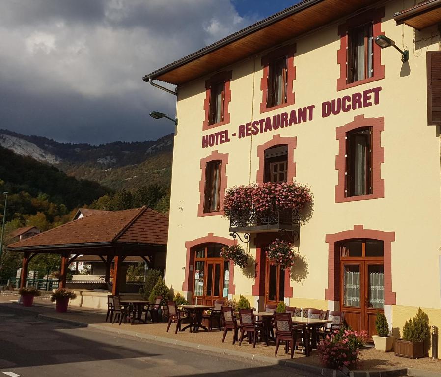 um restaurante com mesas e cadeiras em frente a um edifício em Hôtel Ducret em Champfromier