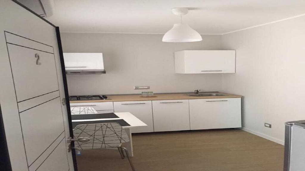 cocina con armarios blancos, mesa y silla en Mini appartamenti a Catanzaro Lido, en Catanzaro Lido