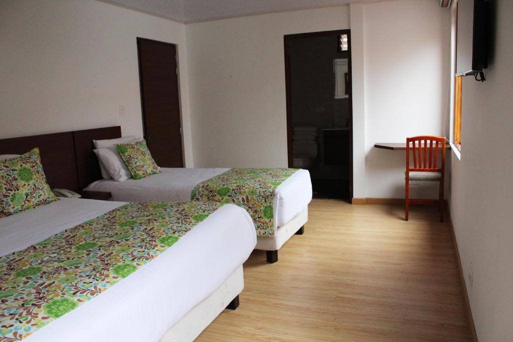 a hotel room with two beds and a table at Hotel Cacique Real in Zipaquirá