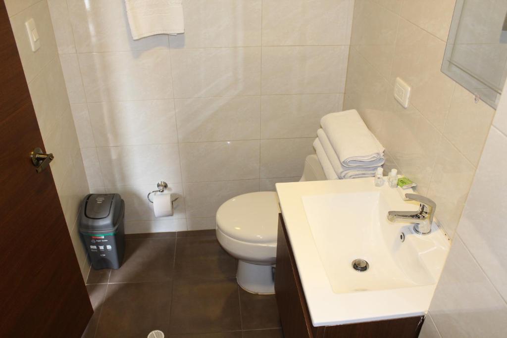a bathroom with a white toilet and a sink at Hotel Cacique Real in Zipaquirá