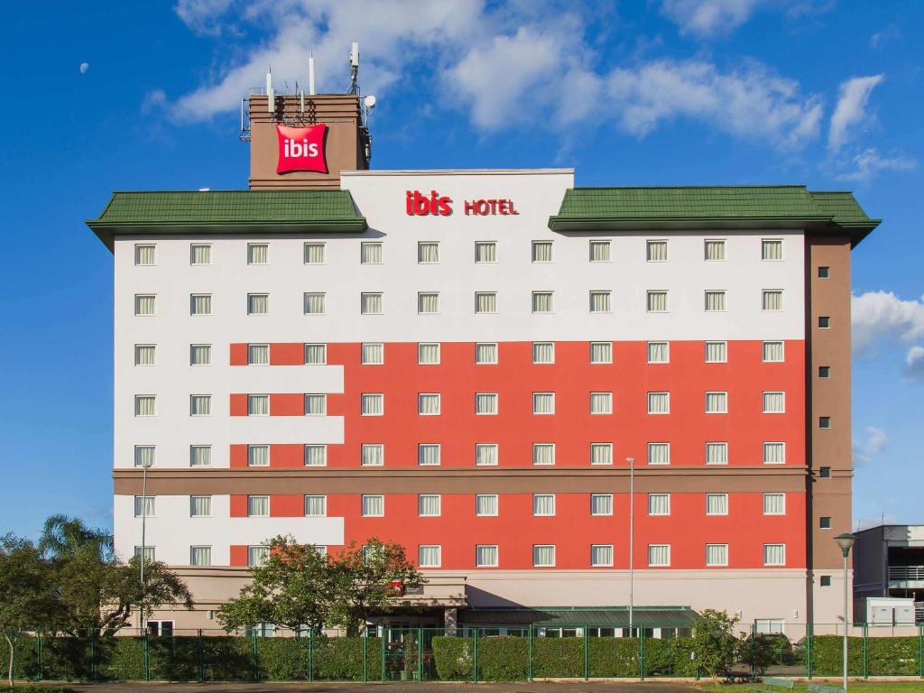 un gran edificio rojo y blanco con una señal de autobús. en ibis Porto Alegre Aeroporto en Porto Alegre