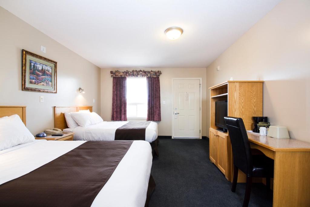 a hotel room with two beds and a desk at West Country Inn in Drayton Valley