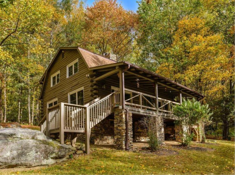 a log cabin in the woods with a wooden deck at Eagle's Rest Lodge in Hendersonville