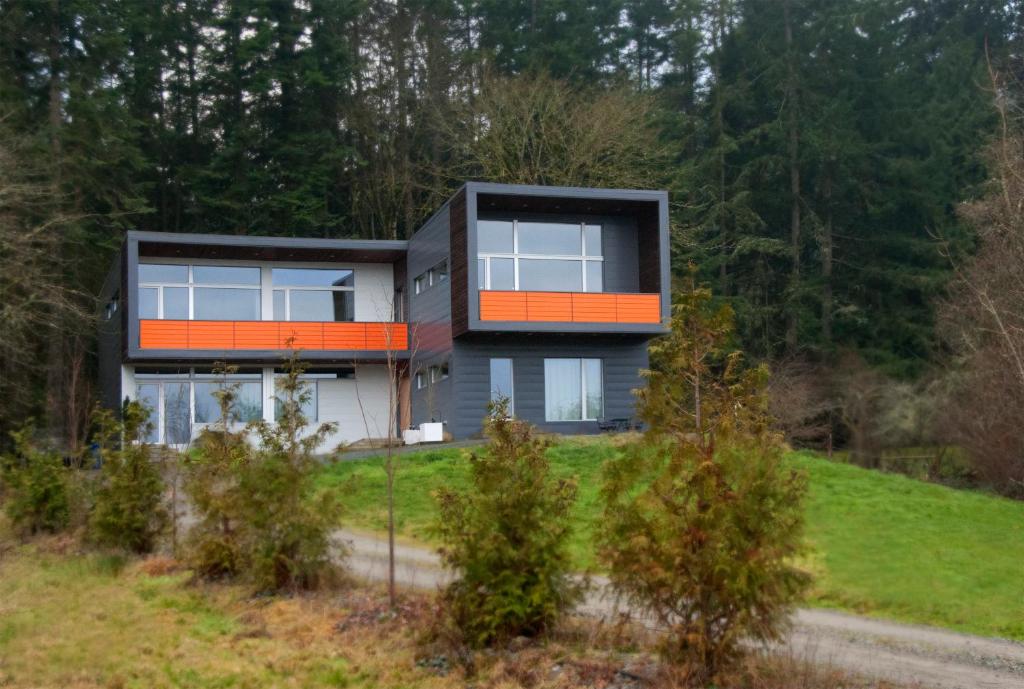 a house on top of a hill with trees at The Cube in Cowichan Bay