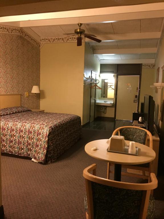a hotel room with a bed and a table and a table at Red Carpet Inn in Hot Springs