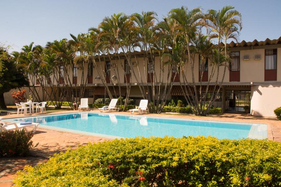 uma piscina em frente a um edifício com palmeiras em Coesa Hoteis em Casa Branca