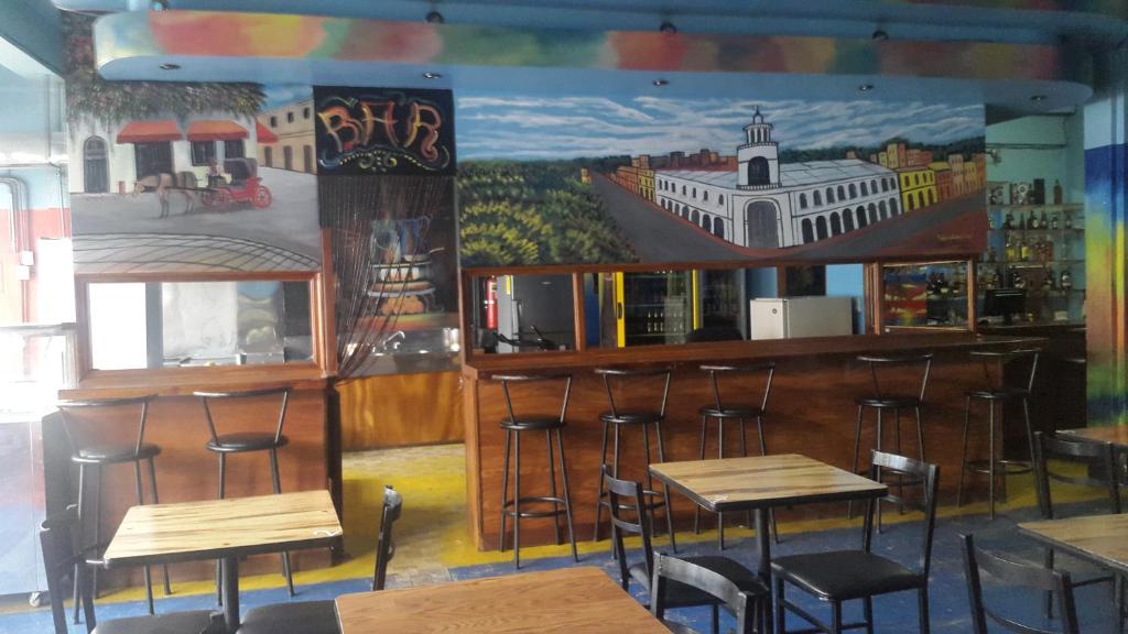 eine Bar mit Hockern und Wandmalereien in der Unterkunft Hotel Latino in San José