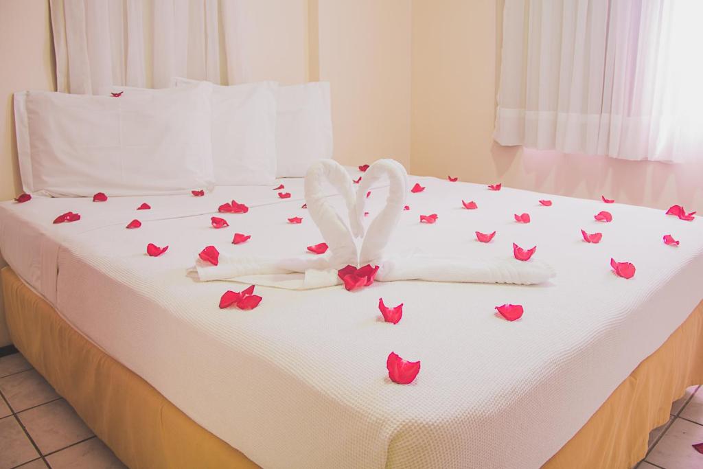 un lit avec des roses rouges et une feuille blanche dans l'établissement JOH Blue Ocean Flat Hotel, à Fortaleza