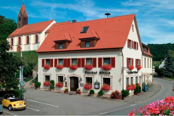 a large white building with a red roof at Flair Hotel Gasthof zum Hirsch in Hayingen