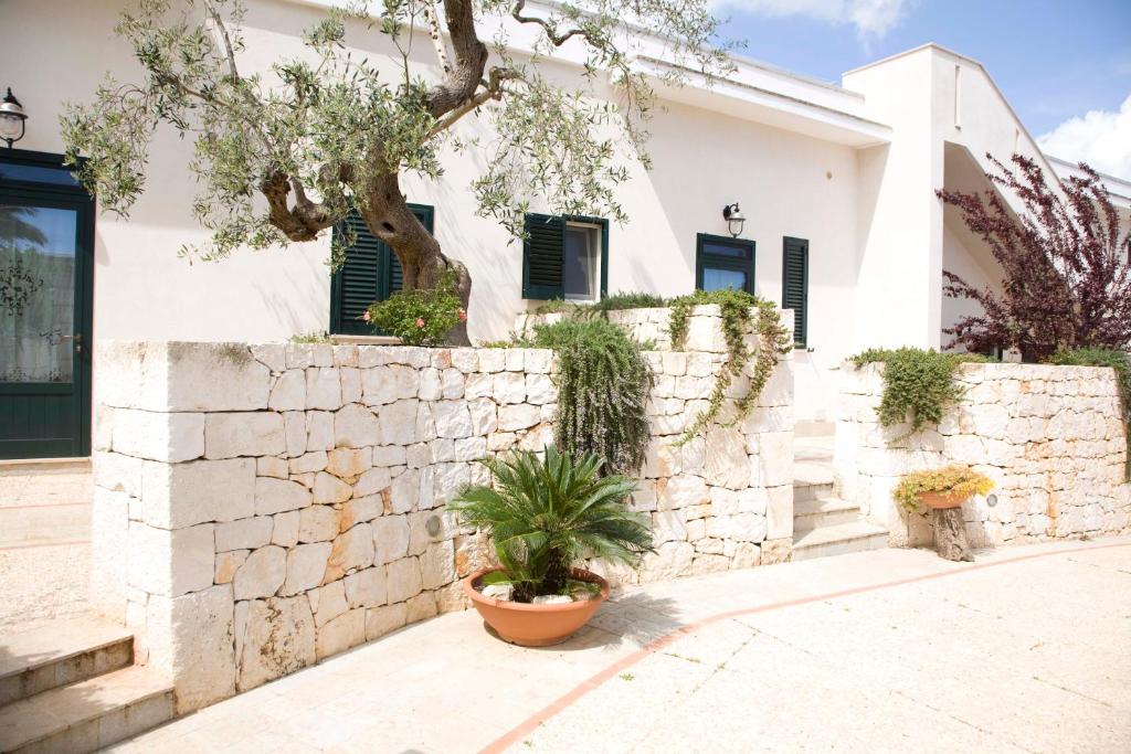 a white house with a stone wall and a tree at Masseria Asciano in Ostuni