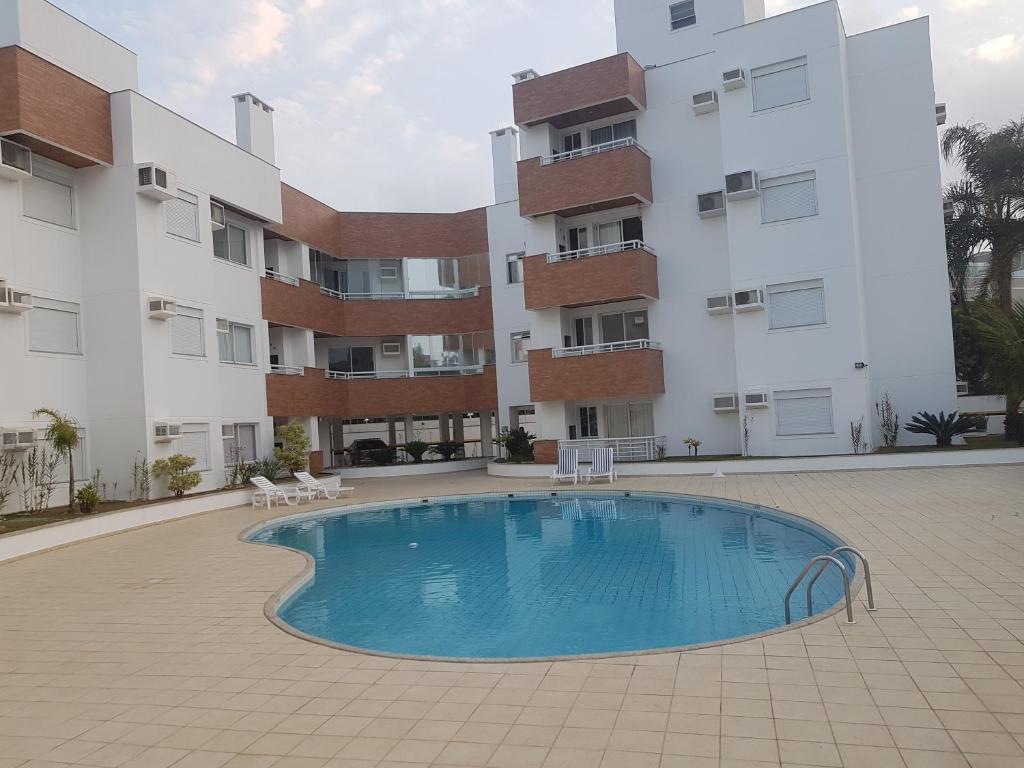 a swimming pool in front of a building at Apto de 02 qtos no Ingleses - Florianopolis - SC in Florianópolis