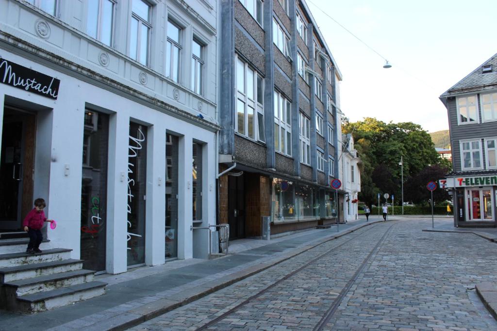 Eine leere Stadtstraße mit Gebäuden und einem Mädchen, das auf der Straße steht. in der Unterkunft MB Apartments in Bergen