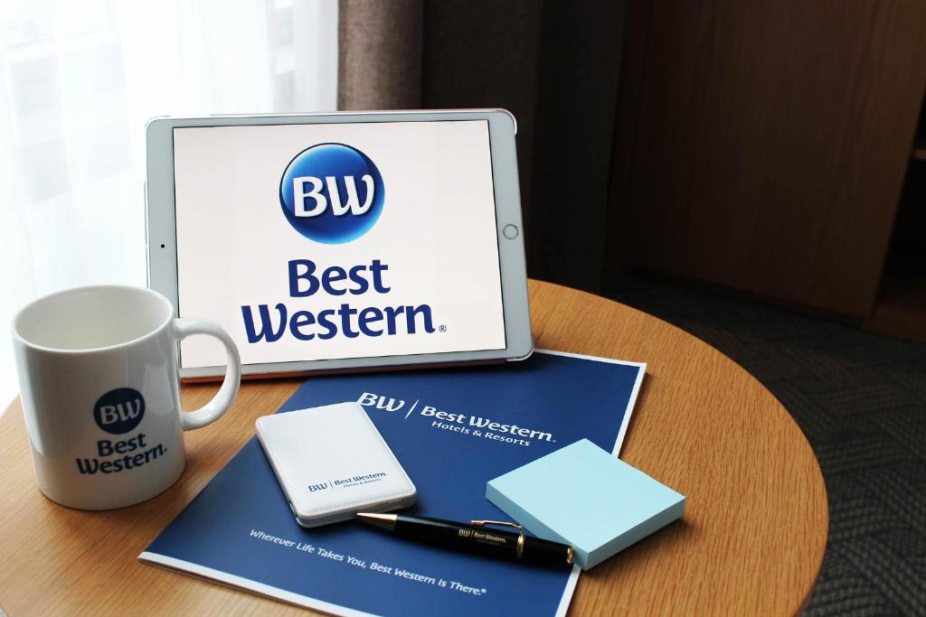 Best Western Haeundae Hotel في بوسان: جهاز كمبيوتر محمول موجود على طاولة بجوار كوب