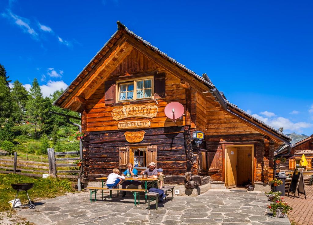 two people sitting at a table in front of a log cabin at Ferienhütte Hoitahüttl in Mauterndorf