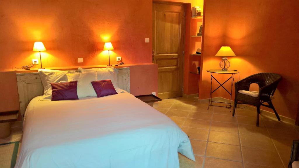 a bedroom with a large white bed and a chair at Le Clos des Pierres Dorées in Theizé