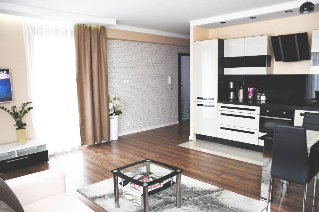 a living room with a table and a kitchen at Apartament Wilga Park in Krakow