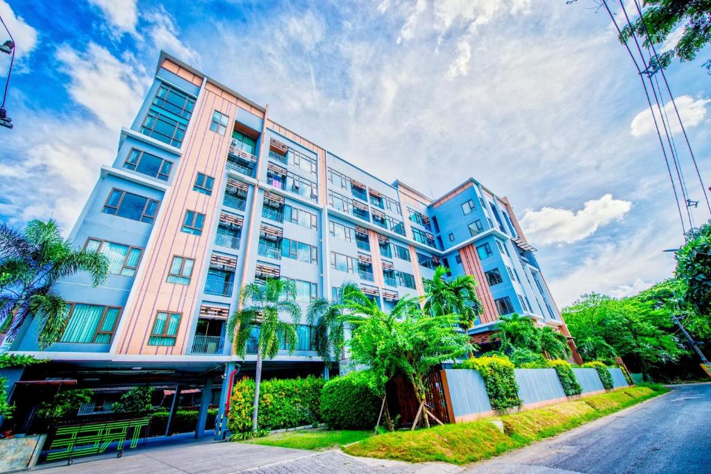 a tall building with palm trees in front of a street at Tree Boutique Resort in Chiang Mai