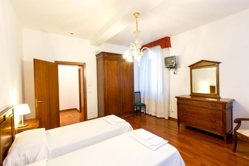 a bedroom with two beds and a dresser and a mirror at Centro Cardinal Urbani in Zelarino