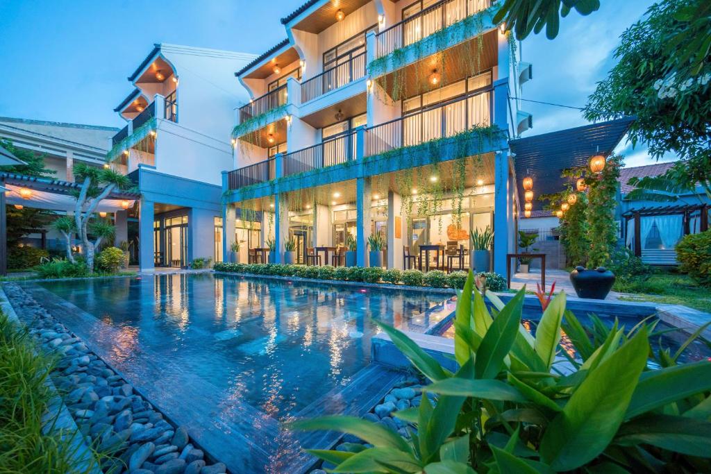 a hotel with a swimming pool in front of a building at Dai An Phu Villa in Hoi An