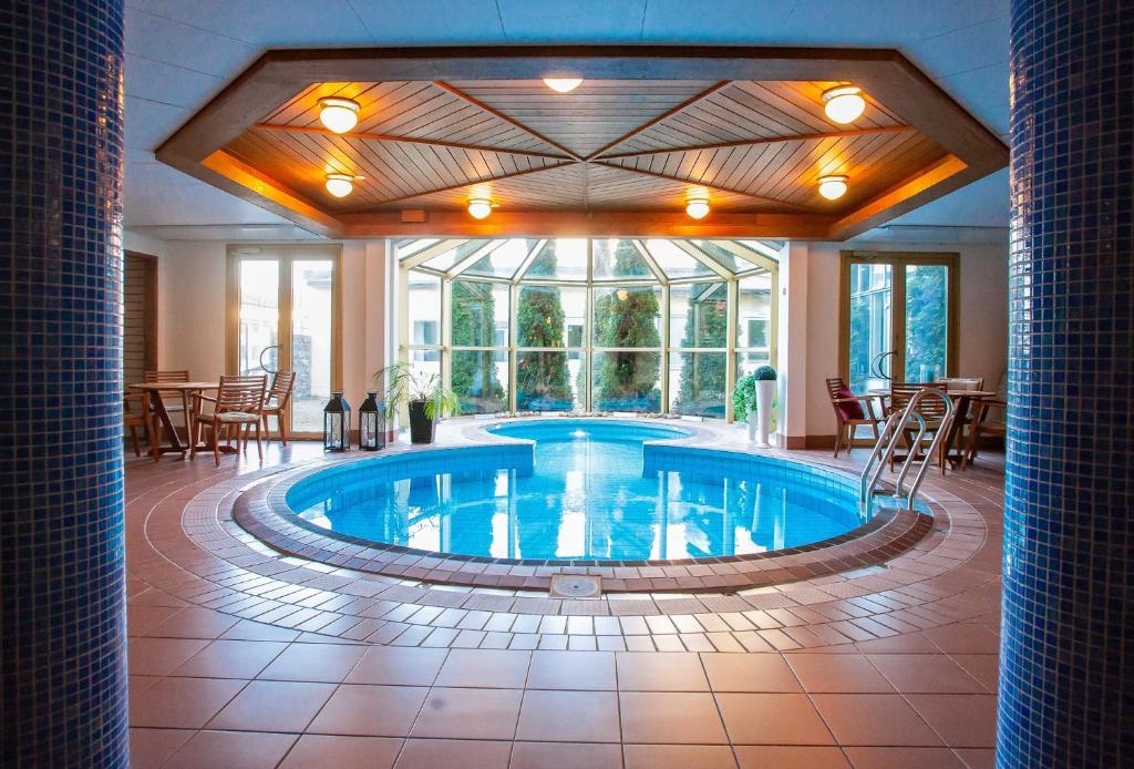 a large pool in a hotel lobby with tables and chairs at Clarion Collection Hotel Smedjan in Sandviken