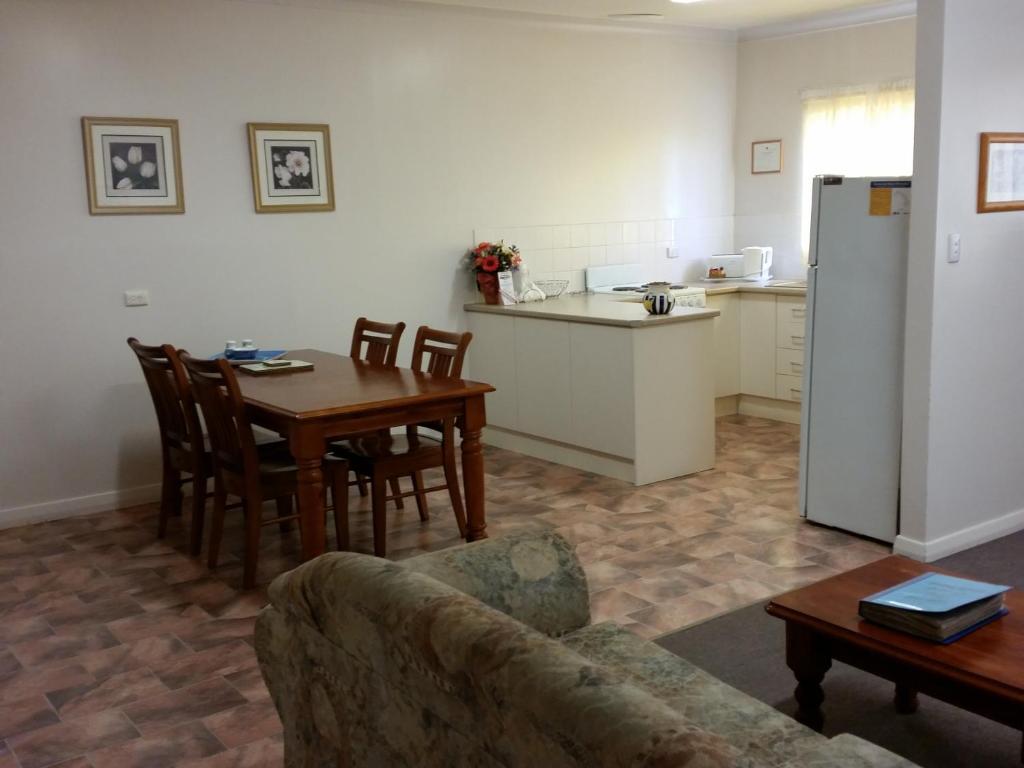 sala de estar con sofá, mesa y cocina en About Town Cottages, en Broken Hill